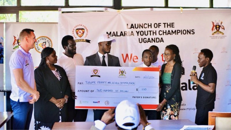 Guests and youth champions present a 200 US dollar award cheque to Tugume Francis and Achola Jemimah Faith at the launch of Malaria Youth Champions Uganda