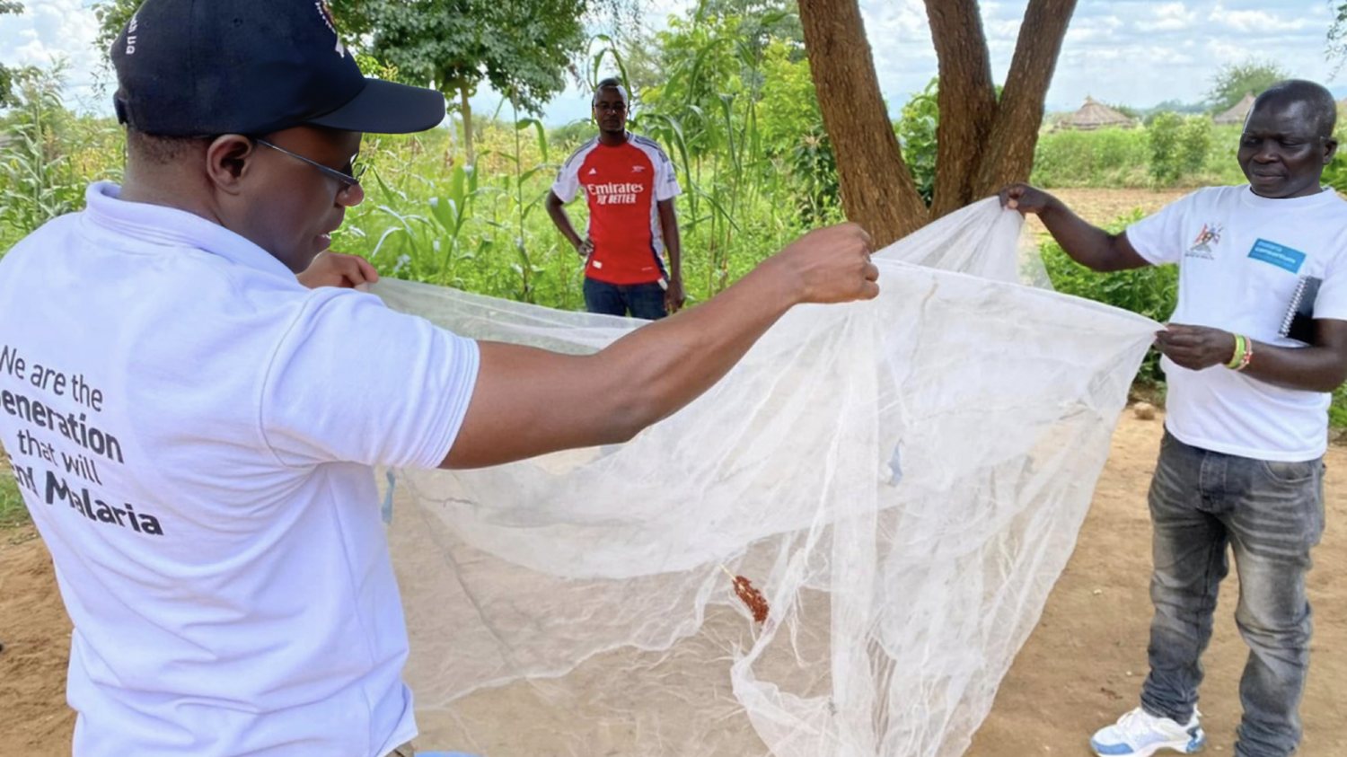 Malaria Youth Champions open out a new mosquito net in a village compound to show families how it works