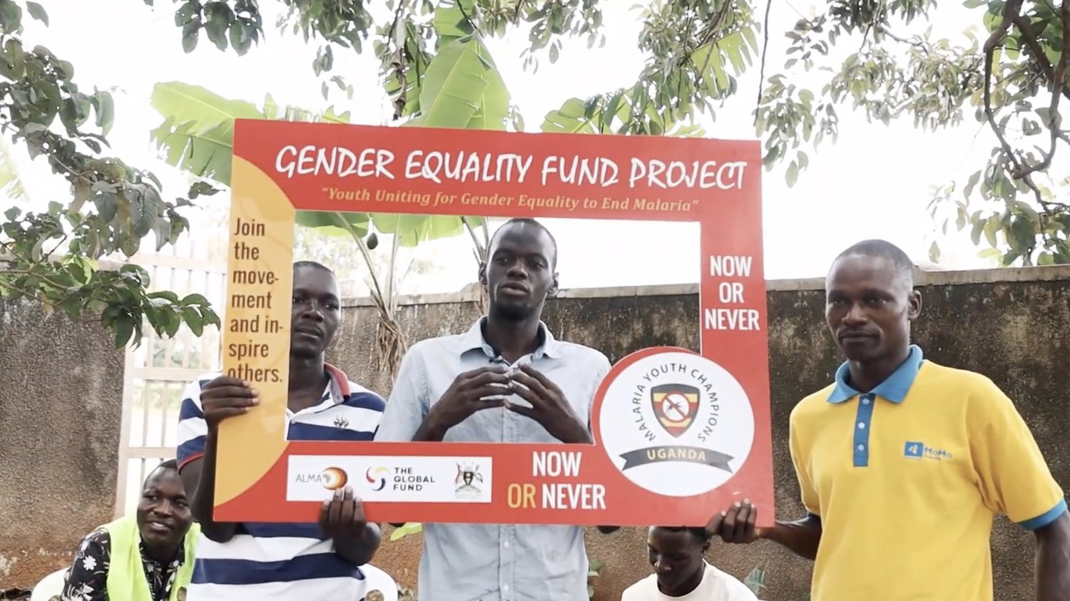 MYCU youth champions hold a Gender Equality Fund Project frame reading 'Youth Uniting for Gender Equality to End Malaria' during the community dialogue in Iganga District