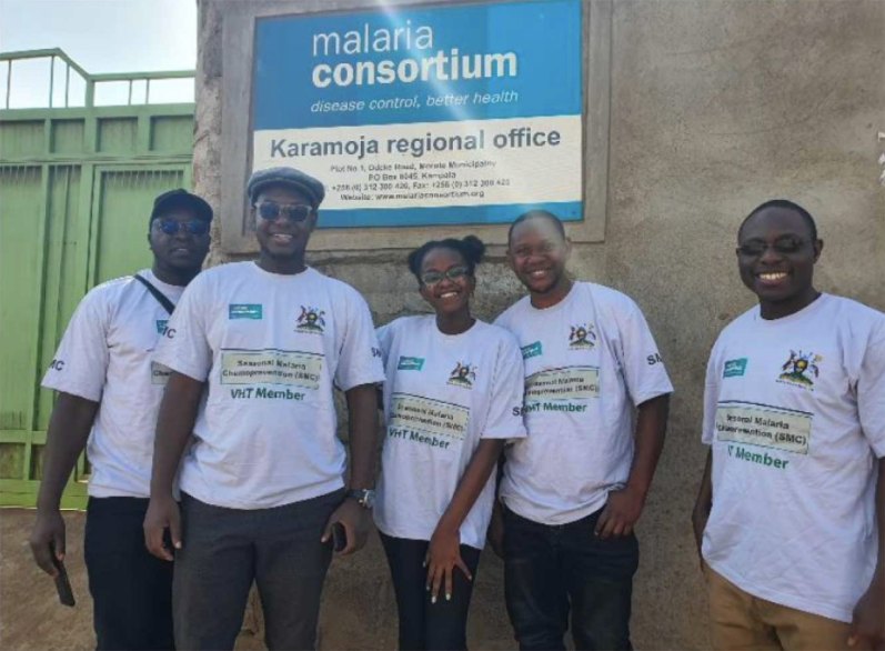 Five Malaria Youth Champions Uganda members in seasonal malaria chemoprevention T-shirts smile outside the Malaria Consortium Karamoja regional office