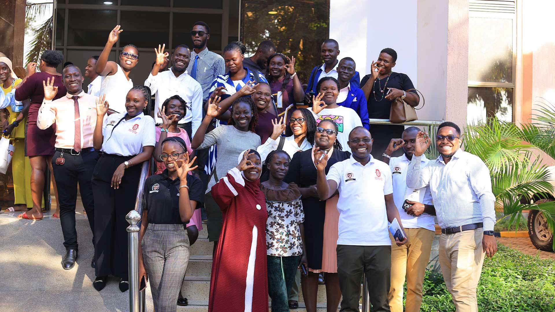Malaria Youth Champions smiling and waving together on the steps outside a training venue