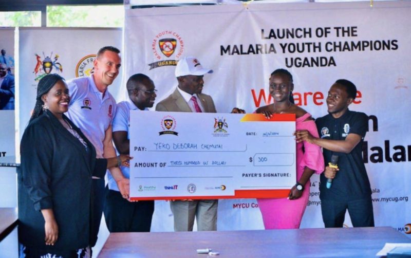 Yeko Deborah Chemutai holds a 300 US dollar award cheque with guests at the launch of Malaria Youth Champions Uganda
