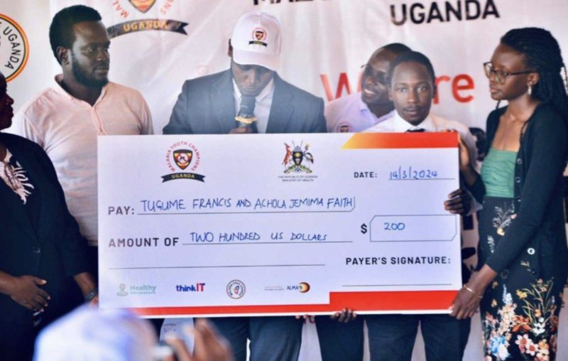 Tugume Francis and Achola Jemimah Faith receive a 200 US dollar award cheque at the launch of Malaria Youth Champions Uganda
